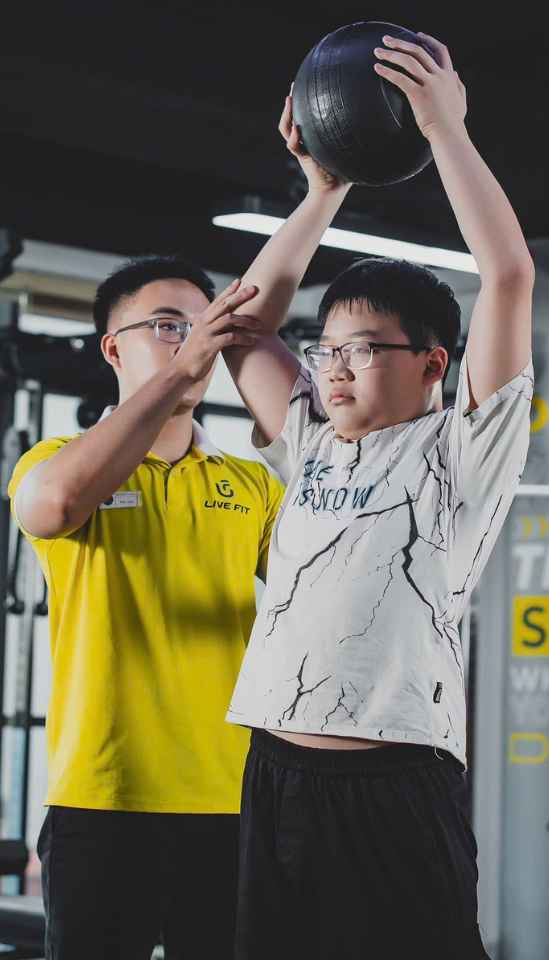 Huấn luyện viên tại Live Fit đang chỉ bạn nhỏ luyện tập